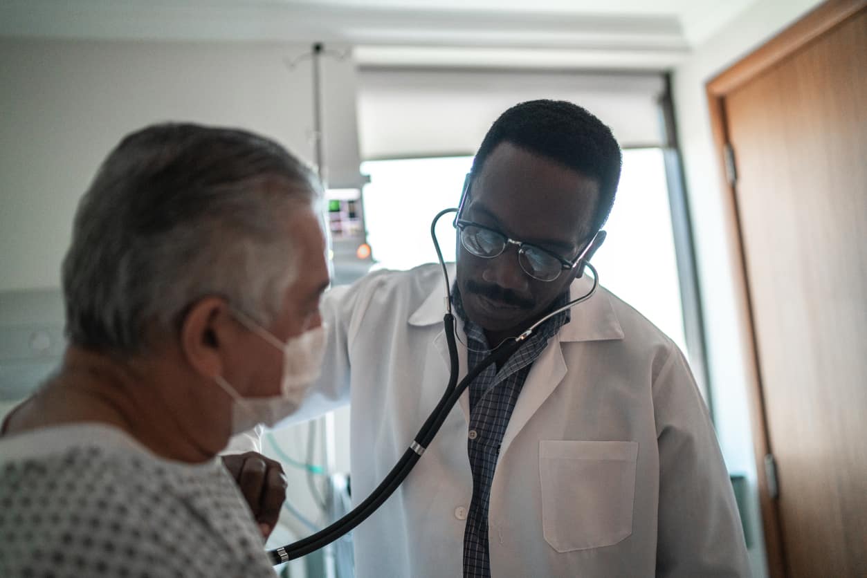 Doctor listening patient's heartbeat at hospital room